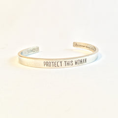 Protect This Woman Pewter adjustable cuff bracelet front view.  "Protect This Woman" displayed on face of bracelet.